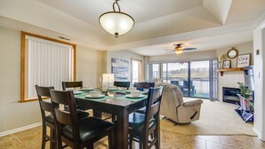 Un coin repas avec une table dressée pour quatre personnes, un ventilateur de plafond et une vue sur l’extérieur grâce à de grandes fenêtres.
