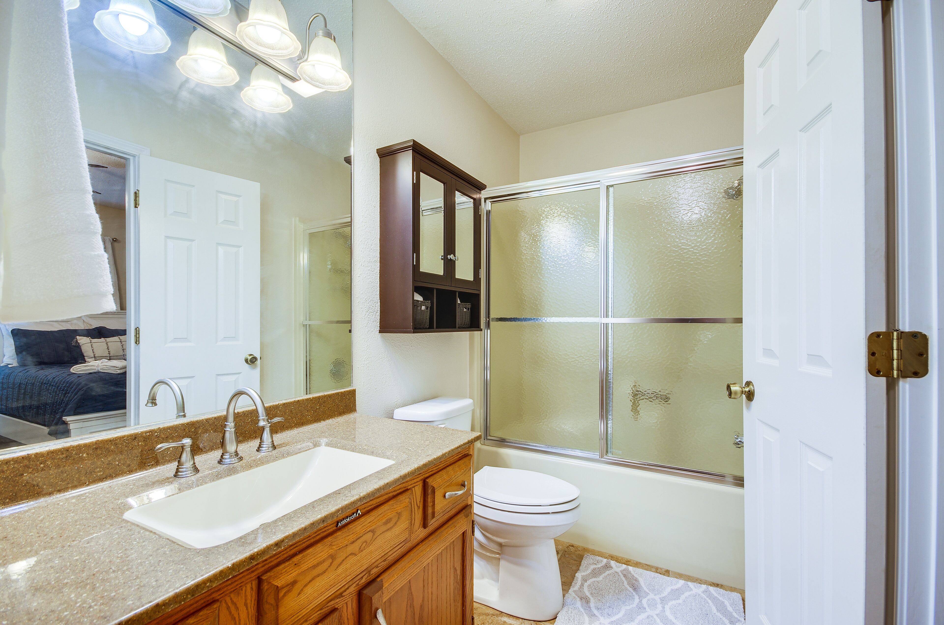 Une salle de bain équipée d’un lavabo, d’un miroir, d’un meuble de rangement, de toilettes et d’une douche à parois de verre.