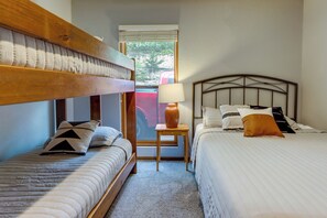Ein Zimmer mit zwei Betten, einem Fenster und einer Lampe.
