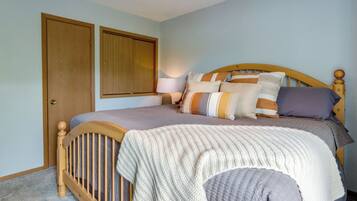 Een slaapkamer met een houten bed, een nachtkastje, een lamp en twee deuren.