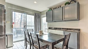 Una cocina con una mesa de comedor y sillas, un refrigerador y armarios.