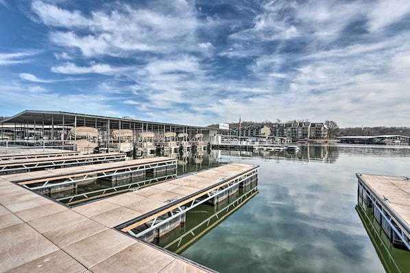 A marina with docking platforms, a covered structure, and a distant building with a sign.