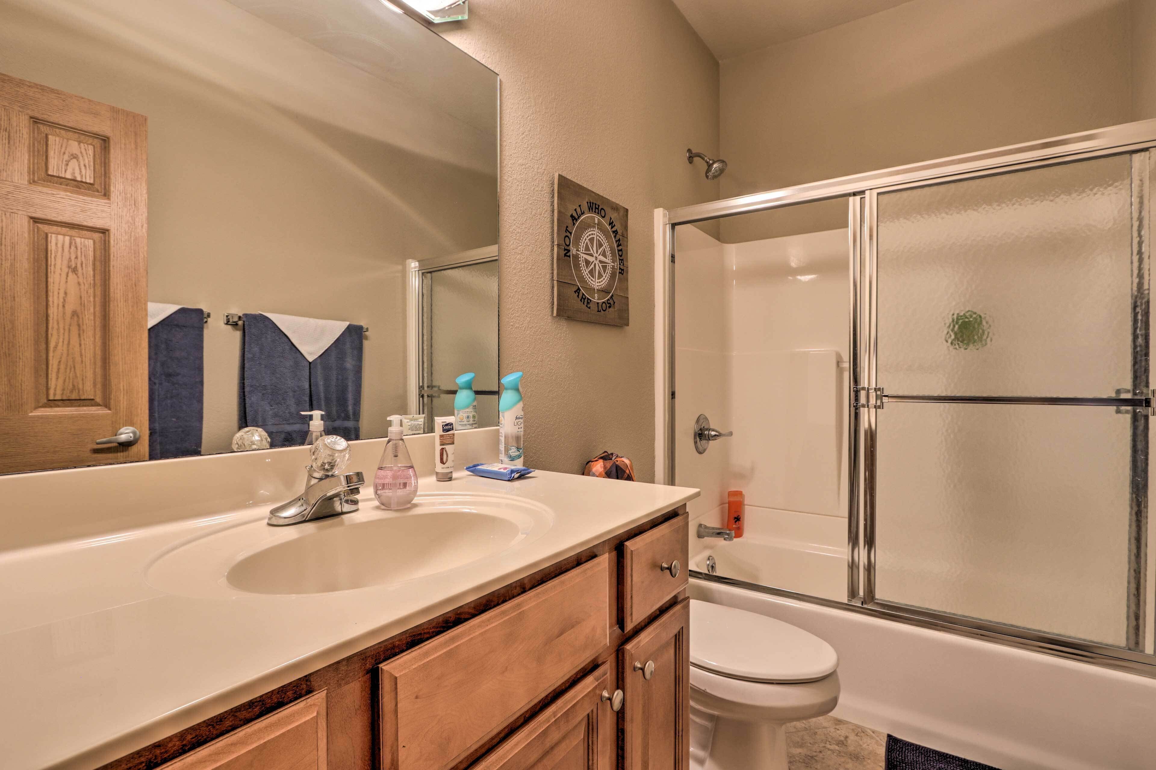 A bathroom with a double sink, a toilet, and a glass shower enclosure.