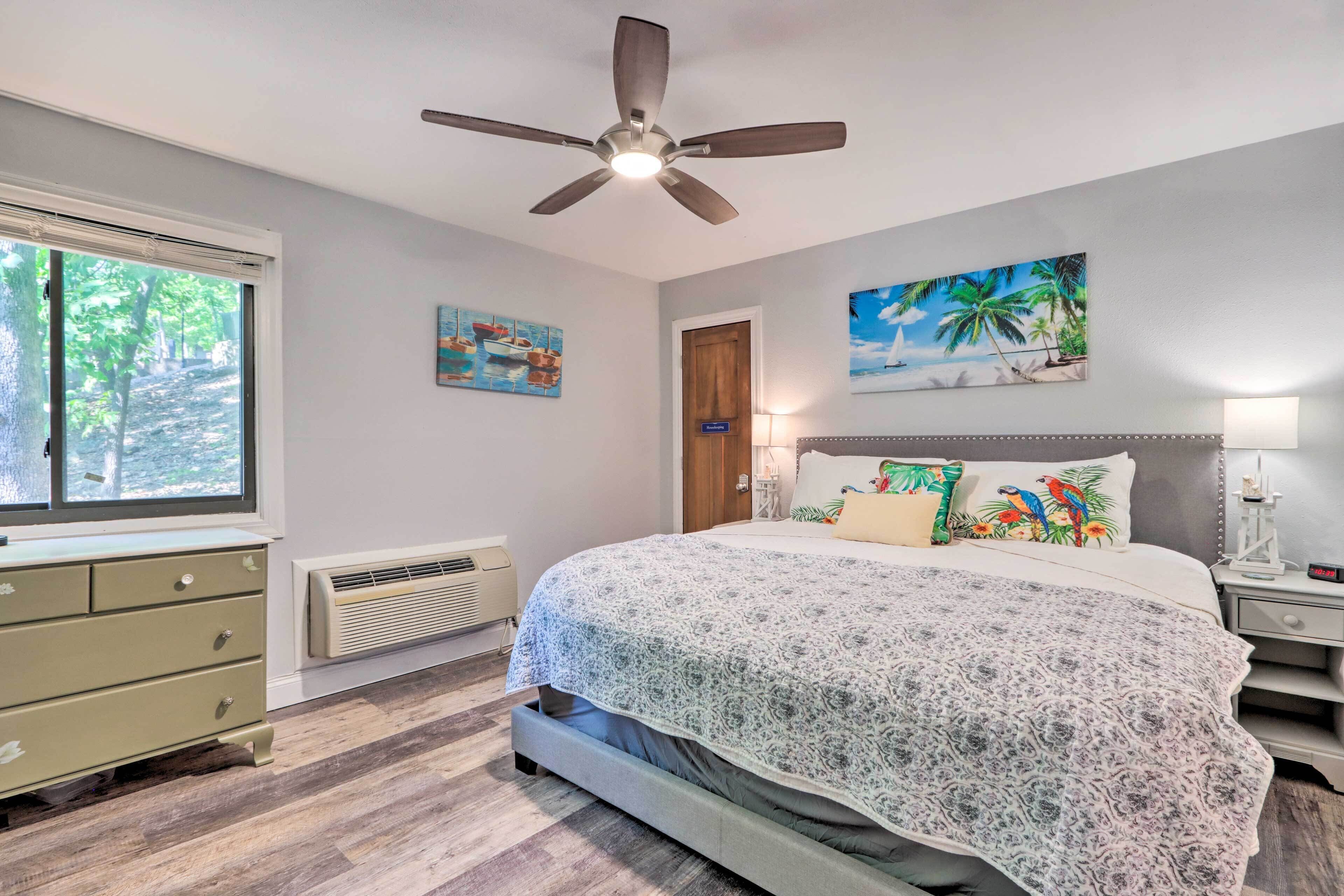 A bedroom with a bed, a ceiling fan, a window, a dresser, and wall art.