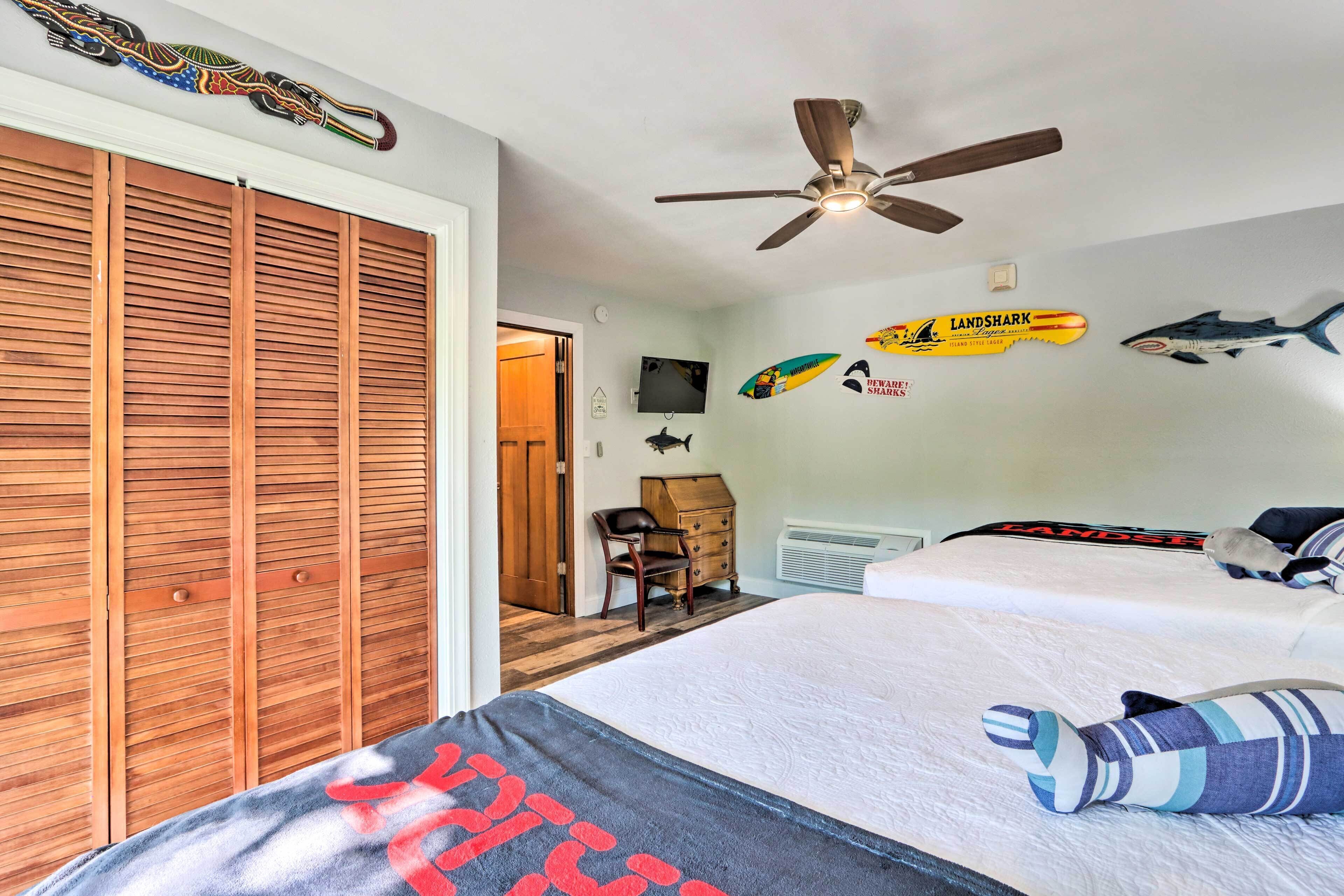 A bedroom with a bed, a ceiling fan, a wooden wardrobe, and wall decorations including shark decals.