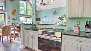 A kitchen with white cabinets, a stainless steel stove, and a dining area with wicker chairs.