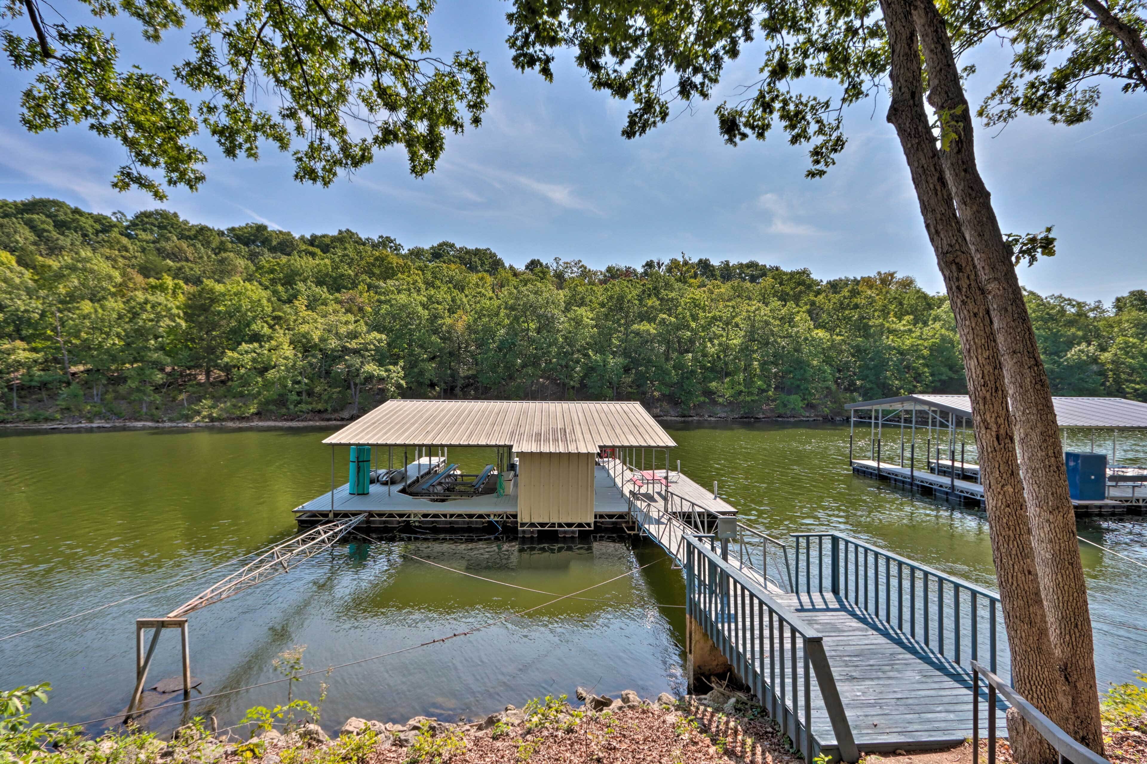 A wooden dock with a small building, a covered seating area, and a metal railing.