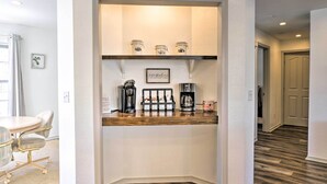 Ein kleiner Küchenbereich mit einer Holzausziehtheke, einer Kaffeemaschine und Gläsern auf einem Regal.