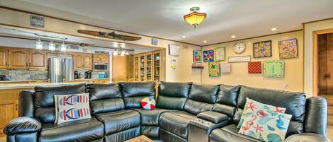A living room with a sectional sofa, a wooden coffee table, and a kitchen in the background.