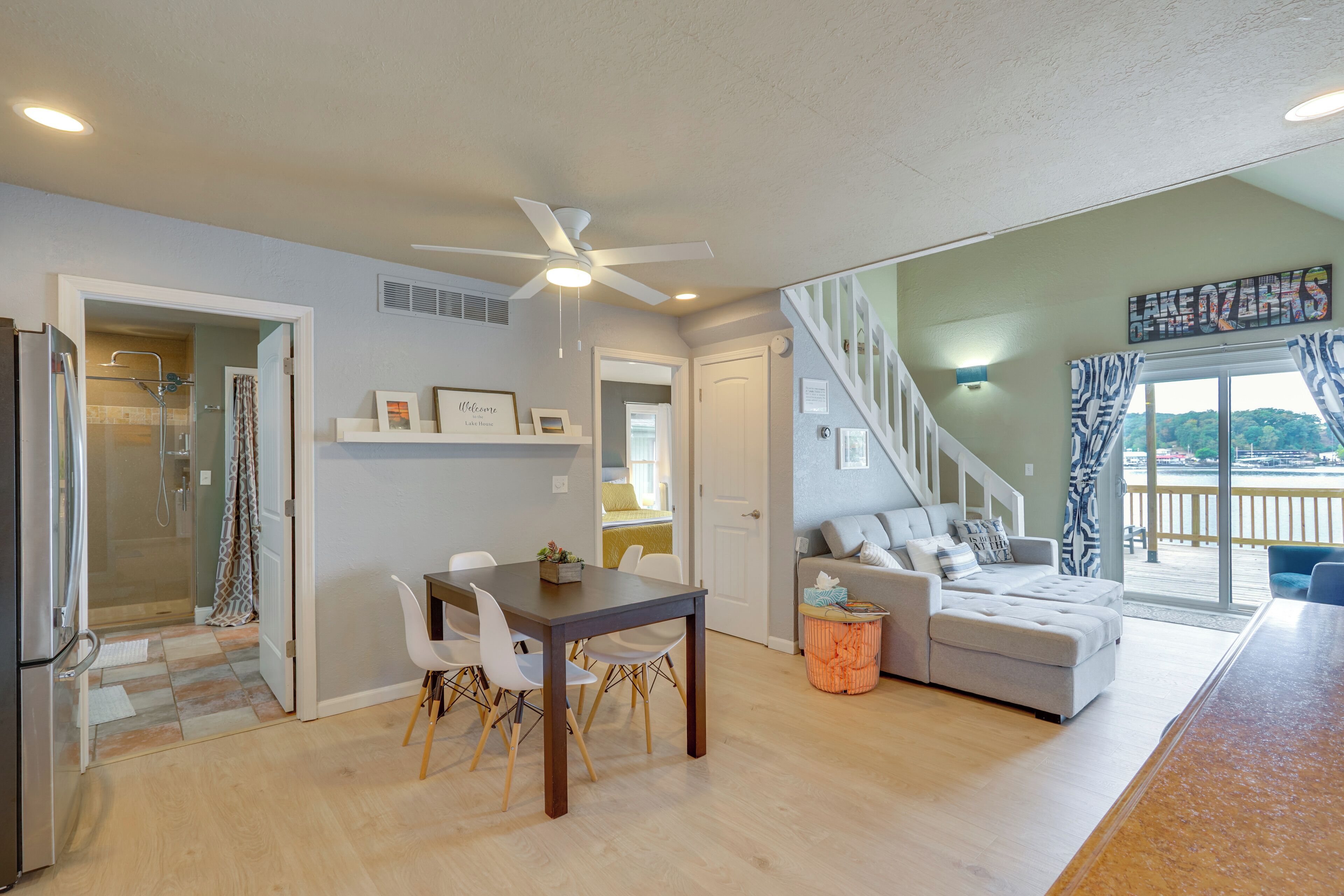 A modern living space with a dining area, a sofa set, a staircase, and a view of the outdoors.