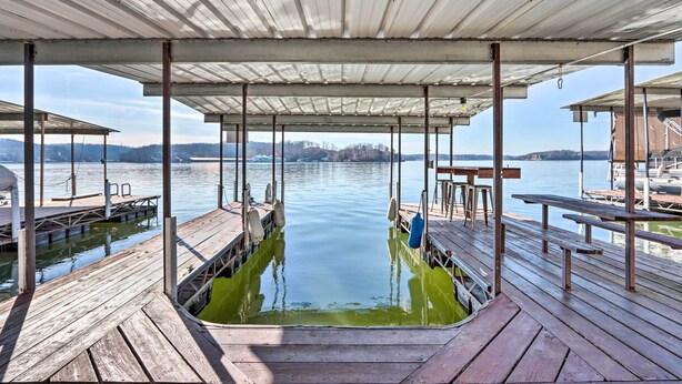 Un muelle de madera con un área de estar cubierta que da vista a un cuerpo de agua tranquilo.