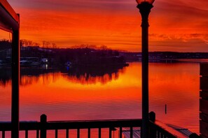 A sunset over a calm body of water with a silhouette of trees and buildings in the background. - Lakefront Ozarks Home: Deck + Boat Dock! (Linn Creek)