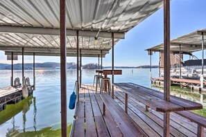 A wooden dock with benches and a covered area overlooking a calm body of water. - Lakefront Ozarks Home: Deck + Boat Dock! (Linn Creek)