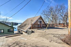 Una casa con techo inclinado, una terraza de madera y vista a un lago.