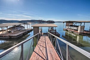 Un muelle de madera que conduce a un embarcadero con zonas de estar cubiertas y un pequeño refugio.