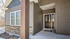 Une maison moderne avec des fondations en pierre, une porte d’entrée et un petit jardin devant.