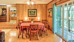 Un comedor con una mesa y sillas de madera, una araña y obras de arte enmarcadas en las paredes.
