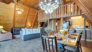 Un intérieur rustique en bois, comprenant un coin repas, un canapé et un escalier menant à un niveau supérieur.