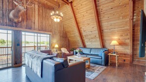 L'intérieur d'une cabane en rondins, avec un grand canapé, une table basse et une tête de cerf accrochée au mur.
