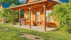 Una baita di legno con portico coperto, area salotto esterna e barbecue.