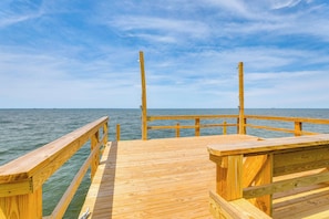 A wooden pier extending into calm water under a clear sky.