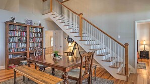 A dining area with a wooden table and chairs, a bookshelf, and a staircase. - Lakefront Retreat w/ Game Room & Private Dock! (Bonneau)