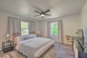 A bedroom with a bed, nightstands, a desk, a chair, and a ceiling fan.