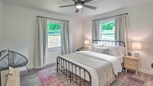 A bedroom with a bed, bedside tables, a ceiling fan, and windows with curtains. - Lakefront Townville Gem w/ Boat Dock & Kayaks (Townville)