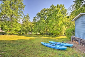 A grassy yard with two kayaks and a blue building. - Tranquil Townville Gem With Kayaks (Townville)