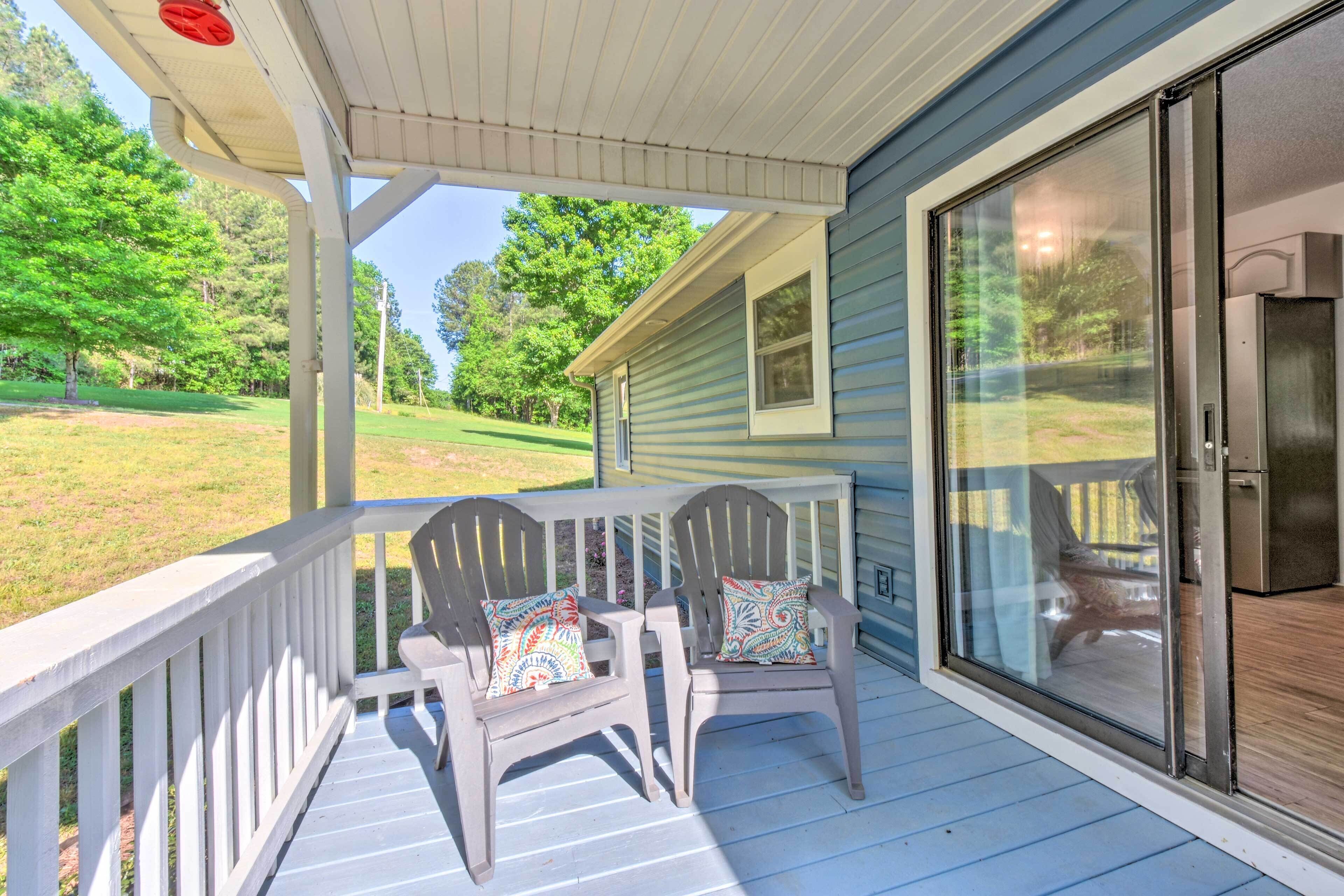 A porch with two Adirondack chairs and a sliding glass door.