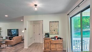 A spacious living room with a large TV, a wooden cabinet, and a poster on the wall. - Lakefront Townville Gem w/ Boat Dock & Kayaks (Townville)