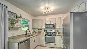 A modern kitchen with stainless steel appliances, white cabinetry, and a granite countertop. - Lakefront Townville Gem w/ Boat Dock & Kayaks (Townville)