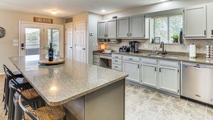 A kitchen with granite countertops, white cabinets, a built-in dishwasher, and a window with blinds. - Dock & Water Slide: Family Lake of the Ozarks Home (Gravois Mills)