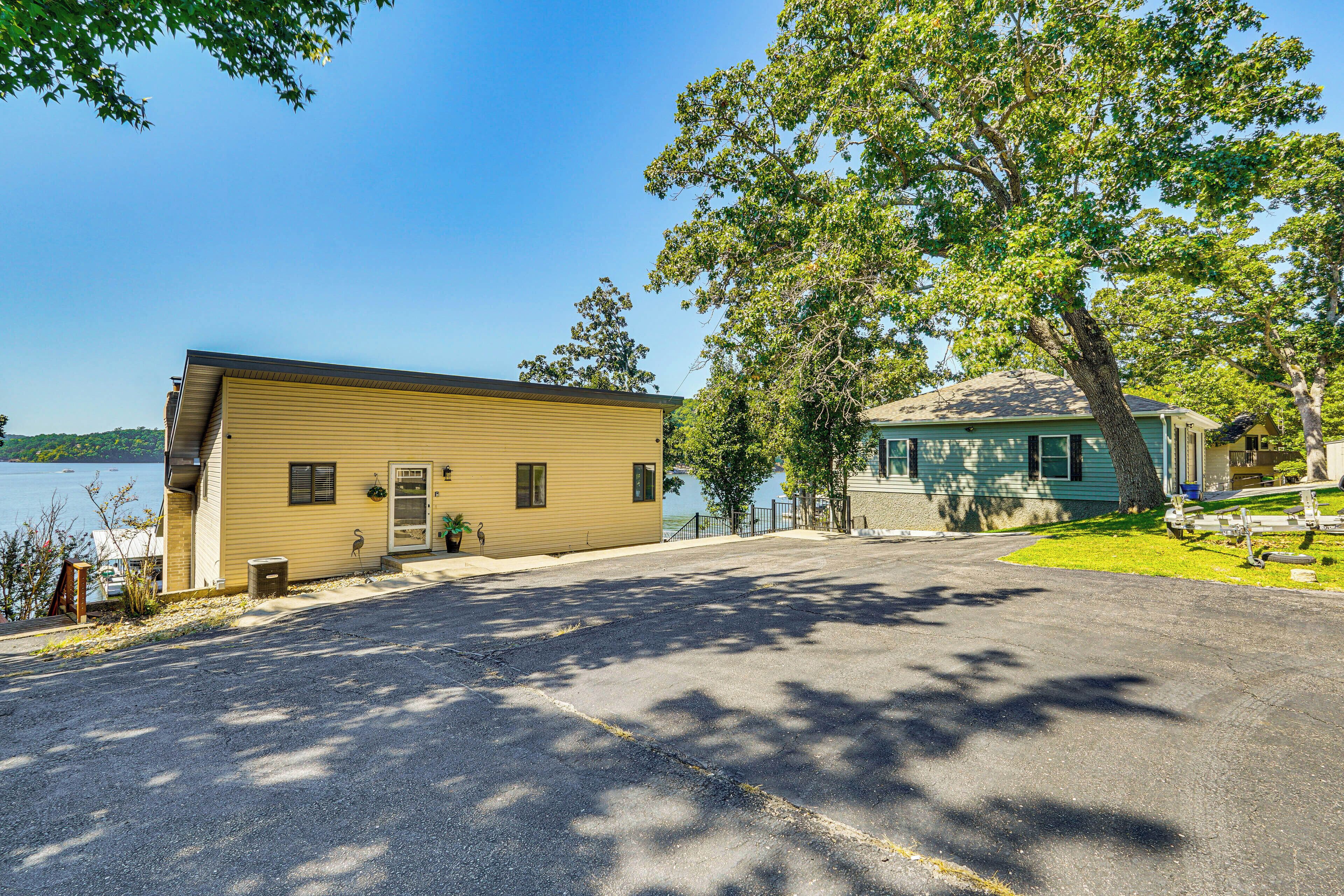 A yellow building with a garage, a tree in front, and a lake in the background.