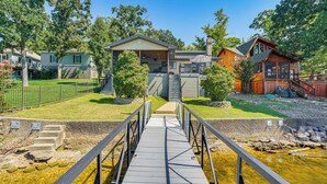 A wooden bridge leading to a building with a covered porch and a staircase. - Dock & Water Slide: Family Lake of the Ozarks Home (Gravois Mills)