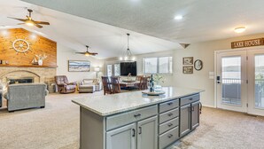 A spacious living area with a fireplace, a dining table, and a kitchen island. - Dock & Water Slide: Family Lake of the Ozarks Home (Gravois Mills)