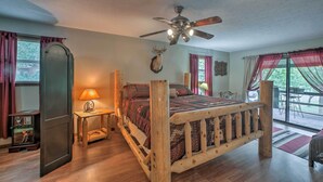 A wooden bed with a headboard, a ceiling fan, a lamp, and a deer head on the wall. - Waterfront Home w/ Fire Pit on Table Rock Lake (Golden)