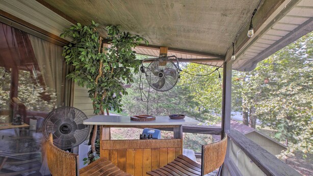 A covered outdoor seating area with wooden furniture, a fan, and a table with a bowl and camera. - Waterfront Home w/ Fire Pit on Table Rock Lake (Golden)
