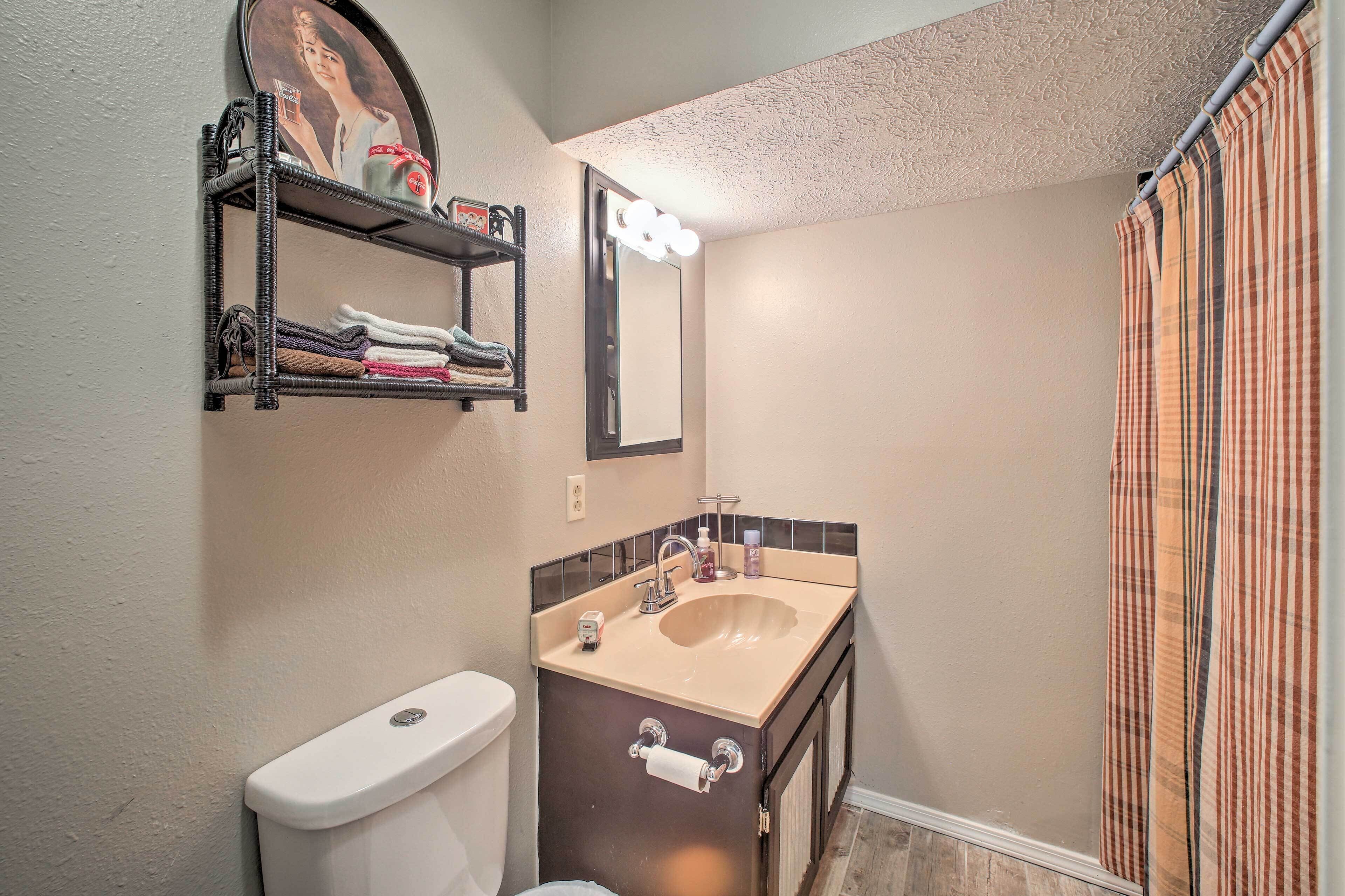 A bathroom with a toilet, sink, mirror, and towel rack.