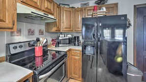 A kitchen with wooden cabinets, a stainless steel refrigerator, a stove, and a microwave. - Waterfront Home w/ Fire Pit on Table Rock Lake (Golden)