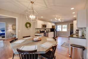 A modern kitchen with white cabinets, a central island, and a dining area with a wooden table and chairs. - Lakefront Westminster Retreat w/ Boat Dock! (Westminster)