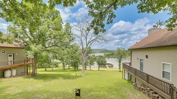 A property with a deck, a grassy yard, and a lake view. - Lakeside Reeds Spring Home w/ Deck & Pool Access! (Kimberling City)