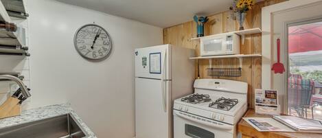 Cocina compacta con refrigerador, estufa, microondas y un reloj en la pared.