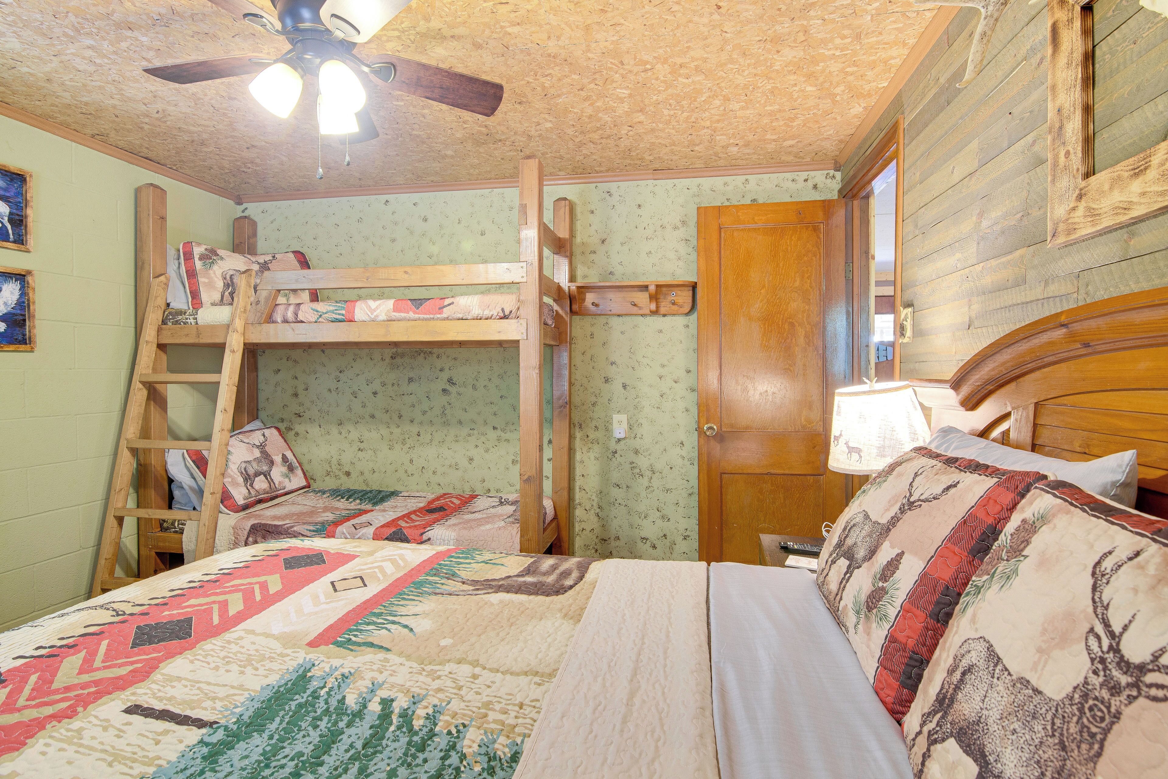 A bunk bed room with a ladder, a wooden door, a ceiling fan, and a quilt with animal patterns.