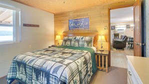 Une chambre à coucher avec un lit, des lampes de chevet, un ventilateur de plafond en bois et un panneau accroché au mur.