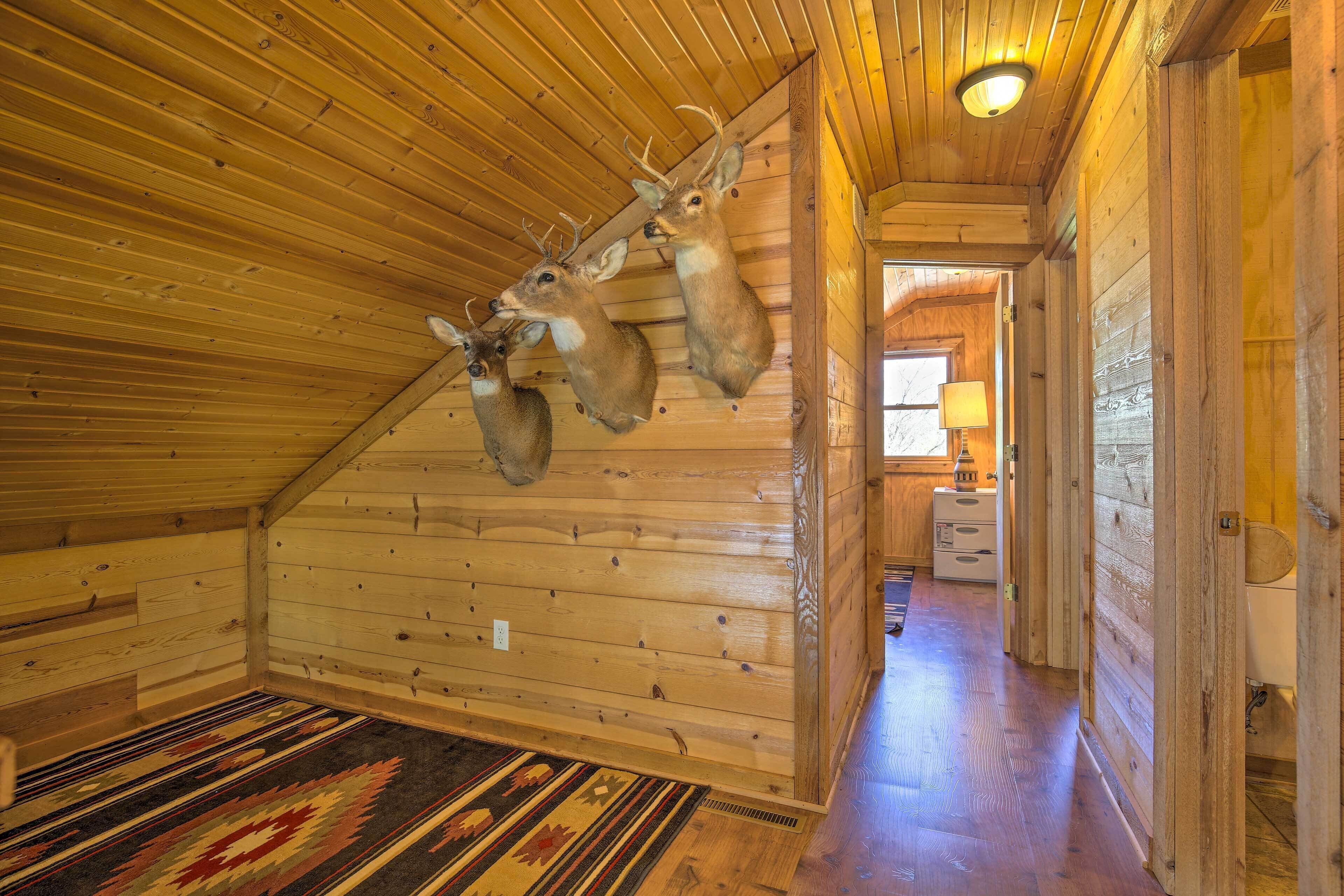 A log cabin interior with wooden walls, a sloped ceiling, and a hallway leading to a bedroom.