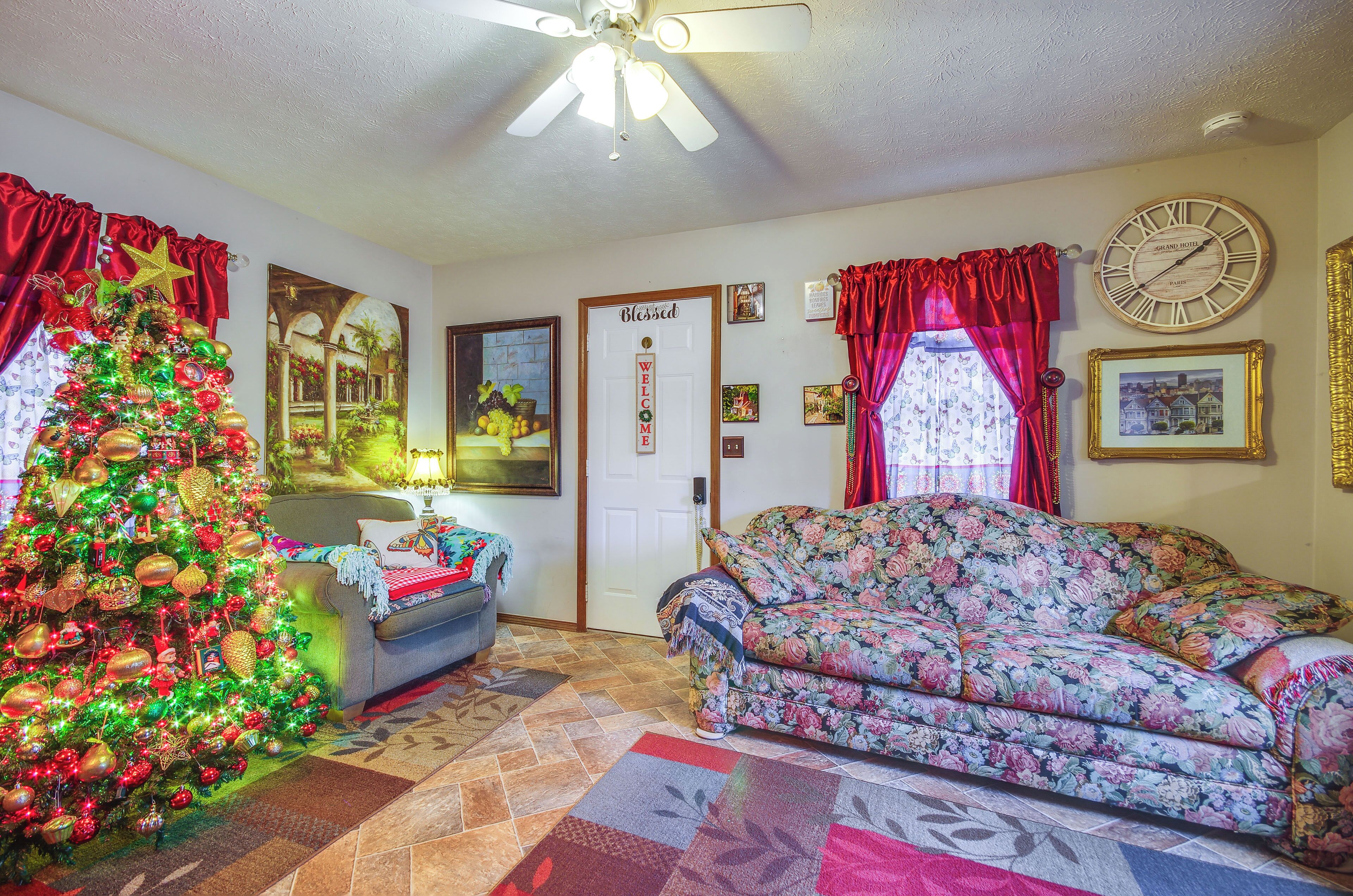 A living room with a Christmas tree, floral sofa, and a clock on the wall.