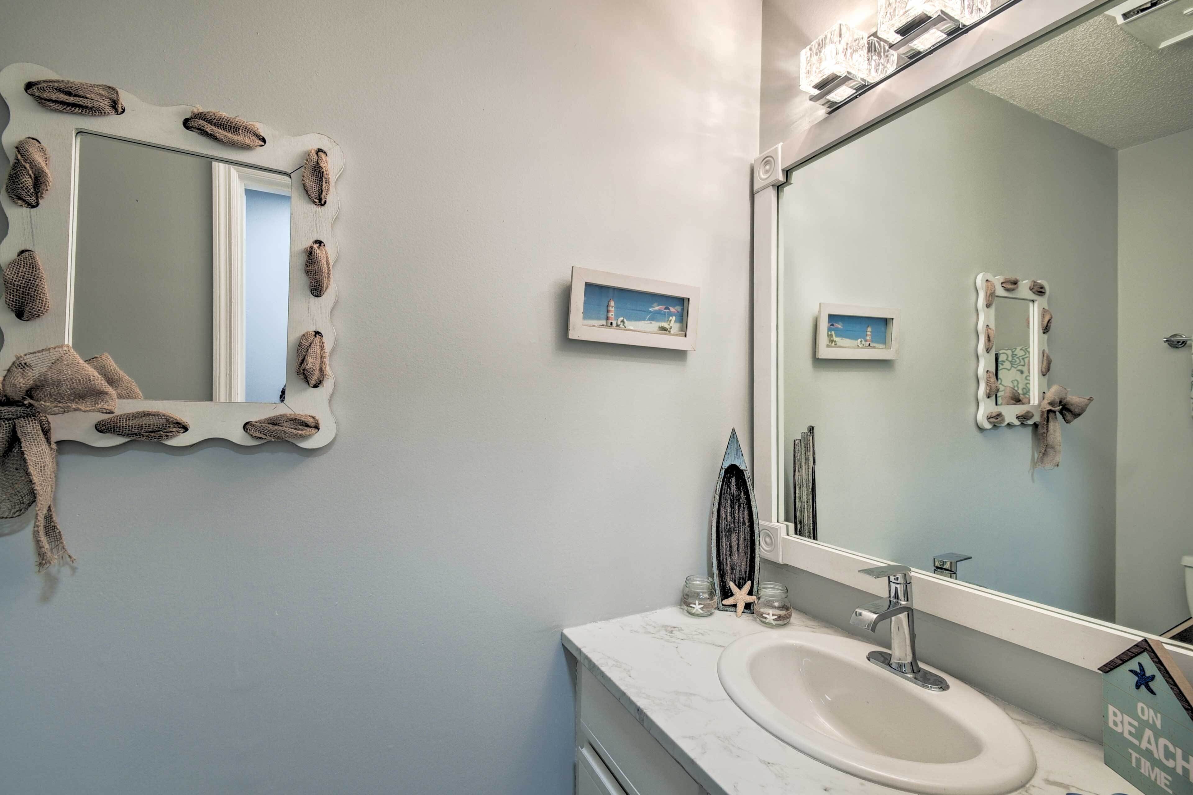 Un baño con un lavamanos blanco, un espejo con marco decorativo y una pequeña foto enmarcada en la pared.