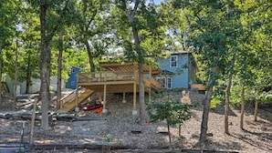 Une maison avec une terrasse en bois, un petit bateau et un étang.