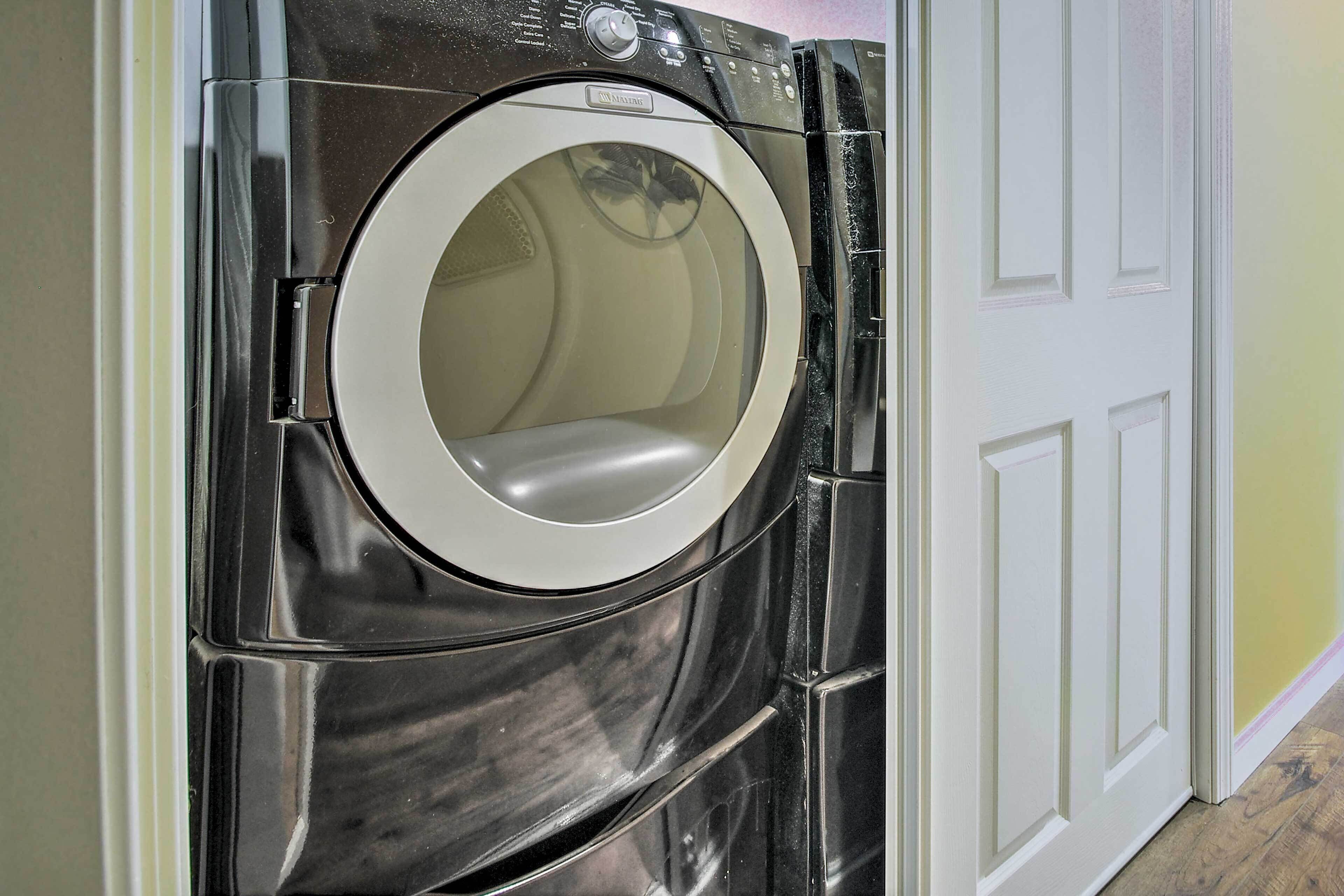 A front-loading washing machine in a laundry room with a white door and wooden flooring.